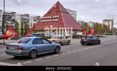 Woronesch, Russland. November 2021. Während des 104. Jahrestages der Oktoberrevolution von 1917 fahren Autos mit roten kommunistischen Flaggen auf der Straße.am 104. Jahrestag der Großen Sozialistischen Oktoberrevolution von 1917 nutzte die russische Regierung die schwierige epidemiologische Situation, um den Bürgern zu verbieten, sich zu Kundgebungen zu versammeln. Aber in Woronesch inszenierten kommunistische Aktivisten eine Reihe von Aktionen. Die bürgerliche Regierung kämpft seit 30 Jahren gegen das historische Gedächtnis des Volkes. Zuerst wurde es am 7. November verboten, den Jahrestag der Revolution in zu feiern Stockfoto