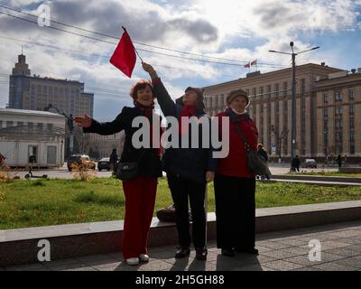 Woronesch, Russland. November 2021. Am 104. Jahrestag der Oktoberrevolution von 1917 hält eine Frau in der Nähe des Leninplatzes eine Fahne.am 104. Jahrestag der Großen Sozialistischen Oktoberrevolution von 1917 nutzte die russische Regierung die schwierige epidemiologische Situation aus, um den Bürgern zu verbieten, sich zu Kundgebungen zu versammeln. Aber in Woronesch inszenierten kommunistische Aktivisten eine Reihe von Aktionen. Die bürgerliche Regierung kämpft seit 30 Jahren gegen das historische Gedächtnis des Volkes. Erstens wurde es am 7. November verboten, den Jahrestag der Revolution im Staat zu feiern Stockfoto