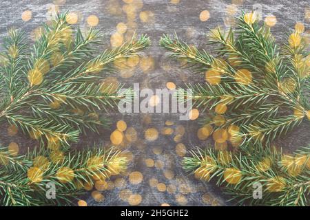 Nahaufnahme des grünen Zweiges des Weihnachtsbaums auf einem hölzernen Vintage-Hintergrund. Gelb glänzende, fröhliche Lichter. Weihnachten und Neujahr. Platz und Hintergrund kopieren Stockfoto