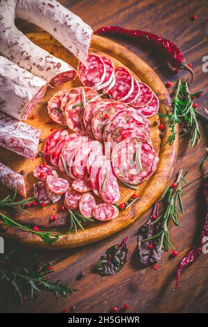 Charcuterie - Sortiment von luftgetrockneten Salami und Wurst auf Holz Schneidebrett mit Gewürzen Stockfoto