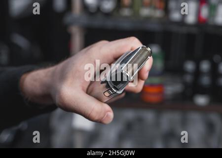 Die Hand eines Friseurs oder Friseurs hält einen automatischen Haarschneider zum Schneiden und Rasieren von Nahaufnahme vor dem Hintergrund des Salons. Stockfoto