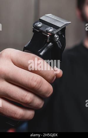 Ein Typ hält eine elektrische Rasiermaschine. Friseursalon. Stockfoto