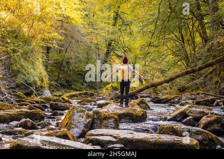 Junge Wanderin, die in einem fließenden Fluss in Passerelle d'Holzarte in Larrau, Frankreich, auf Felsen läuft Stockfoto