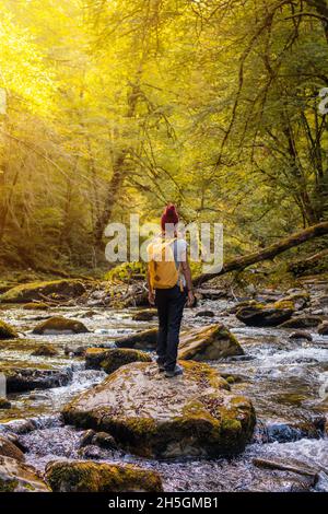 Junge Wanderin, die in einem fließenden Fluss in Passerelle d'Holzarte in Larrau, Frankreich, auf Felsen läuft Stockfoto