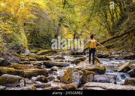 Junge Wanderin, die in einem fließenden Fluss in Passerelle d'Holzarte in Larrau, Frankreich, auf Felsen läuft Stockfoto