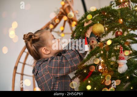 Ein kleines Mädchen schmückt einen Weihnachtsbaum Stockfoto