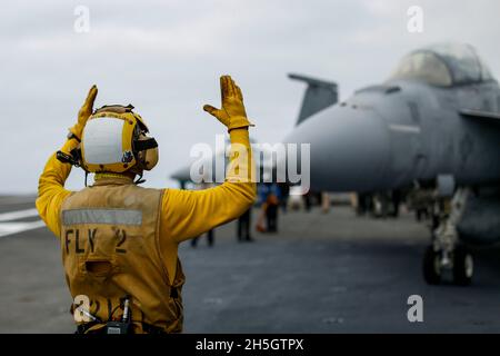 PAZIFISCHER OZEAN (Nov 6, 2021) Aviation Boatswain's Mate (Handling) Airman Julian Fernando aus Yonkers, N.Y., leitet einen F/A-18F Super Hornet, der den 'Black Aces' von Strike Fighter Squadron (VFA) 41 zugewiesen wurde, auf dem Flugdeck der USS Abraham Lincoln (CVN 72). Abraham Lincoln führt derzeit Routineoperationen in der 3. Flotte der USA durch. (USA Navy Foto von Mass Communication Specialist 3rd Class Michael Singley/veröffentlicht) Stockfoto