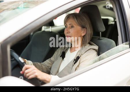 Reife Frau sitzt hinter dem Steuer im Auto Stockfoto