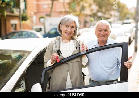 Ein älteres Paar, das neben dem Auto steht Stockfoto