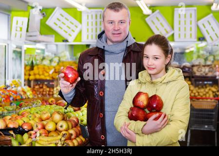 Mädchen mit ihrem Vater, der Äpfel im Obstladen kauft Stockfoto