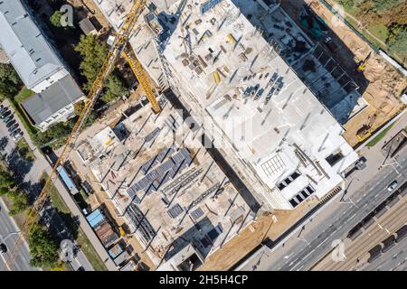 Luftaufnahme von oben auf der geschäftigen Baustelle. Arbeiten Baumaschinen und Baustoffe. Stockfoto