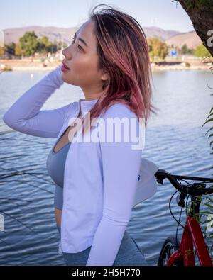 Junge asiatische Frau mit Fahrrad am Ufer eines Sees Stockfoto