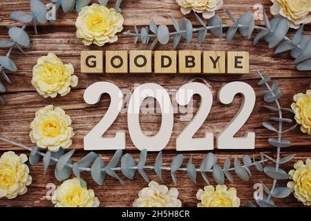 Auf Wiedersehen 2022 Buchstaben mit Blume schmücken auf Holzgrund Stockfoto