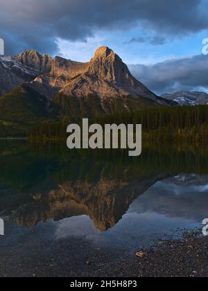 Blick auf den majestätischen Berg Ha Ling Peak in den Rocky Mountains in der Nähe von Canmore, Kananaskis Country, Alberta, Kanada nach Sonnenaufgang im Wasser reflektiert. Stockfoto