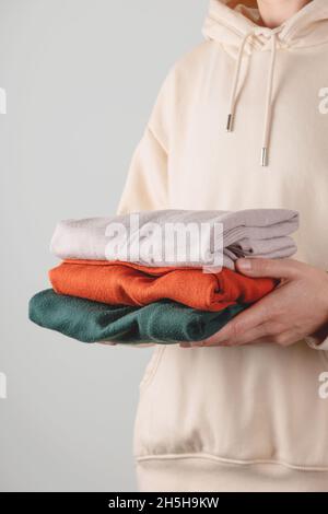 Stapel von Herbst Basic Damen Rollkragenpullover in trendigen Farben in weiblichen Händen. Minimalistischer, einfacher Kleiderschrank. Haushaltswäsche Stockfoto