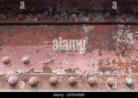 Abblätternde Farbe auf einer rostigen genieteten Brücke. Alte Nieten auf der Brücke. Stockfoto