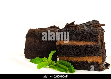 Stück Schokoladenkuchen mit Minzblättern auf weißem, isoliertem Hintergrund. Süßer und leckerer Schokoladenkuchen, ideal für die Kaffeepause, isoliert auf Weiß. Stockfoto