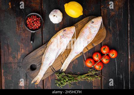 Rohe rote Meeräsche oder Sultanka frisches ganzes Fischset, mit Zutaten und Kräutern, auf altem dunklen Holztisch Hintergrund, Draufsicht flach legen Stockfoto