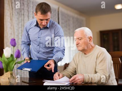 Älterer Mann, der Dokumente mit einem erwachsenen Sohn bespricht Stockfoto