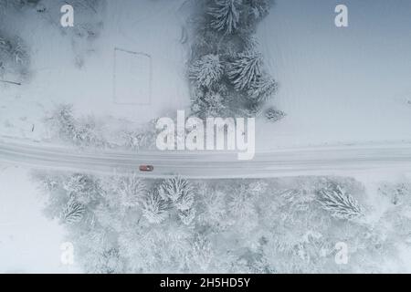 Luftaufnahme von Autofahrten auf verschneiten Bergstraßen im Winter im Nebelwald, Valgerola, Valtellina, Lombardei, Italien Stockfoto