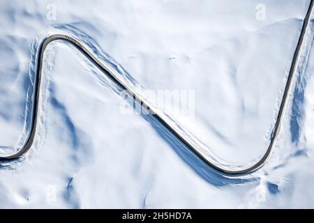 Luftaufnahme der kurvenreichen Bergstraße in der winterverschneiten Landschaft, Dolomiten, Italien Stockfoto