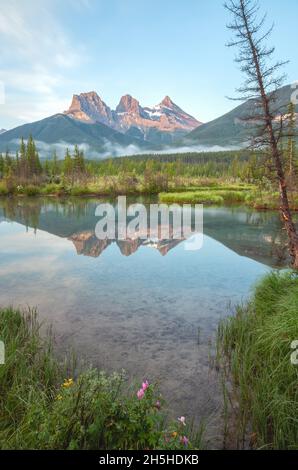 Das Morgenlicht reflektiert die Bergspitzen der drei Schwestern und ihre Reflexionen auf dem Wasser, Canmore, Alberta, Kanada. Stockfoto