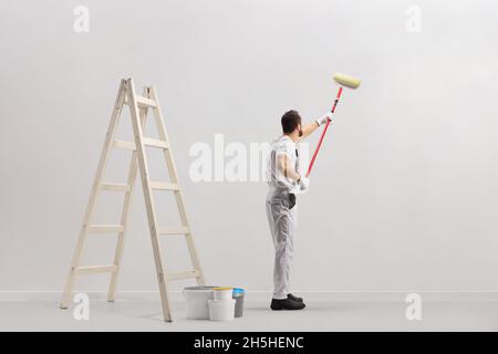 Leiter und Eimer in einem Raum und Dekorateure malen eine Wand isoliert auf weißem Hintergrund Stockfoto