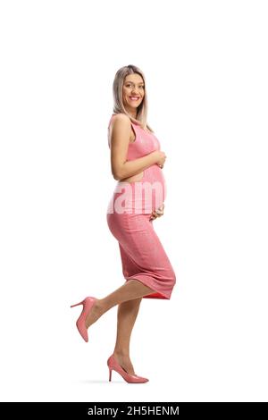 In voller Länge Profilbild einer glücklichen Schwangeren in einem rosa engen Kleid und High Heels isoliert auf weißem Hintergrund Stockfoto