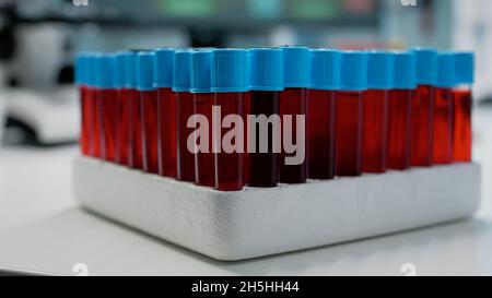Nahaufnahme von Blutproben in Staubsaugern auf einem medizinischen Tablett im Wissenschaftslabor. Transparente Röhrchen mit roter dna-Flüssigkeit für Gentests. Glasflaschen aus farbiger Bio-Lösung Stockfoto