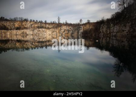 Felsklippen und Herbstbäume spiegeln sich in ruhigem Wasser | ein künstlicher Wasserspeicher, ehemaliger Kalksteinbruch in Krakau, Polen, Steinbruch Zakrzówek Stockfoto