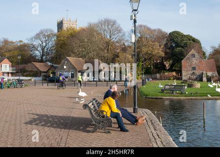 Ein Paar saß auf einer Bank und genoss einen hellen, sonnigen Morgen am Town Quay, Christchurch, Dorset, England, Großbritannien. Stockfoto