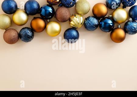 Bunte Weihnachtskugeln Dekoration Rahmen Grenze auf pastellbeige Hintergrund. Flach legen blau, golden und Bronze Weihnachtskugeln Draufsicht. Stockfoto