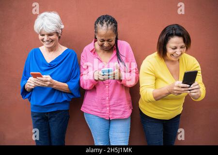 Multirassische ältere Frauen, die Spaß mit Mobiltelefonen im Freien haben - Fokus auf linkes weibliches Gesicht Stockfoto