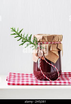 Hausgemachte süße Bio-Pflaumenkonfitüre in einem Glas, das mit Grunge-Papier und Wachssiegel verziert ist. Weihnachten und Winterurlaub einfache Geschenke Idee. Stockfoto