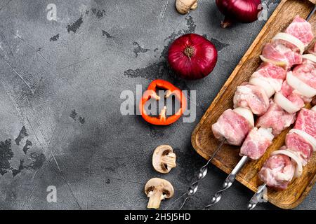 Marinierter Roh-Döner auf Spiessen, Draufsicht flach, mit Platz für Text, auf grauem Steintisch-Hintergrund Stockfoto