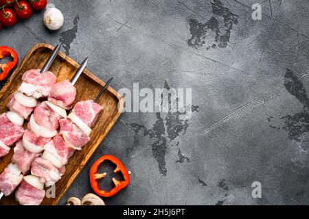 Kebabs rohes Fleisch und Gemüse auf Spiessen, Draufsicht flach liegend, mit Platz für Text, auf grauem Steintisch-Hintergrund Stockfoto