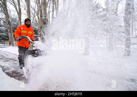 Changchun, Chinas Provinz Jilin. November 2021. Ein Sanitäter entfernt Schnee von einem Fußgängerweg in Changchun, nordöstlich der chinesischen Provinz Jilin, 9. November 2021. Ein andauernder Schneesturm, der am Sonntag begann, hat in Nordostchina Rekordschnee gebracht. Die kalte Welle hat zu einem deutlichen Temperaturrückgang geführt. Quelle: Xu Chang/Xinhua/Alamy Live News Stockfoto