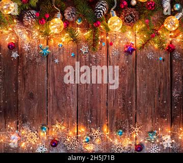 Weihnachten - Dekoration Auf Holz Beleuchtet Mit Lichtern Mit Tannenzweigen Und Ornamenten Stockfoto