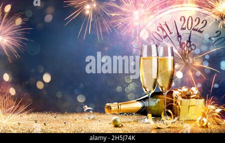 Neujahrsfeier 2022 - Champagner Mit Uhr Und Feuerwerk Bei Nacht - Countdown Bis Mitternacht - Abstrakter Unfokussiert Hintergrund Stockfoto