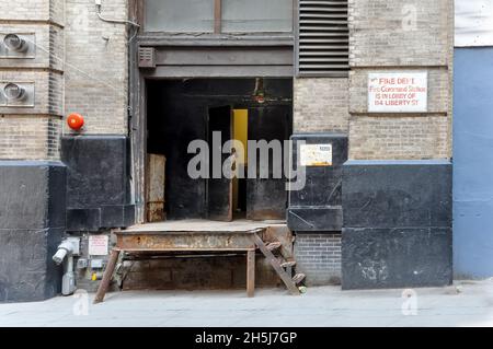 New York City, NY, USA-September 2020; Blick auf eine alte, rostige und verwitterte Stahlladerampe in der Cedar Street mit halb geöffneter Tür Stockfoto