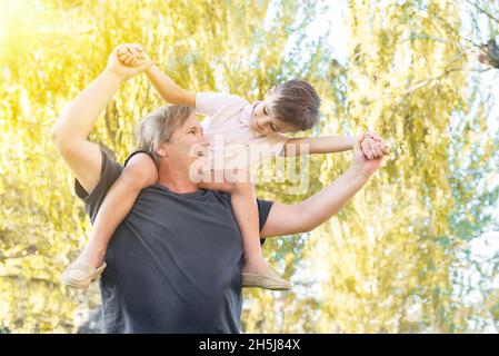 Vater hielt seinen Sohn auf den Schultern und lachte im Park Stockfoto