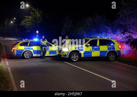 Zwei Polizeifahrzeuge in England im Jahr 2021 blockieren die Straße. Zwei Polizeiautofahrer stehen zur Verfügung. Stockfoto