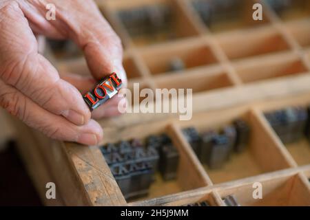 Alphabet Buchstabe Metallblöcke mit WORTLIEBE in der Hand des alten Mannes Stockfoto
