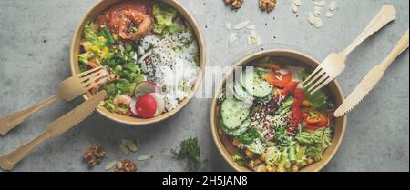 Die Japaner stecken eine Schüssel mit Meeresfrüchten und Salat und eine vegane Schüssel mit Gemüse und Kichererbsen in einen nachhaltigen Lebensmittelbehälter auf grauem Hintergrund. Umweltfreundliche de Stockfoto