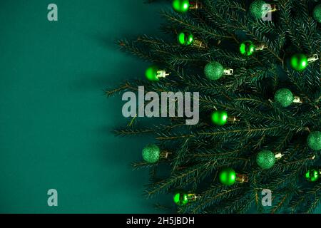 Weihnachtlich grüner Hintergrund. Kiefernzweige, Nadeln und Weihnachtsbäume mit grünen Kugeln. Blick von oben. Für Text platzieren. Weihnachten Natur Hintergrund. Dezember-Stimmungskonzept. Speicherplatz kopieren. Stockfoto