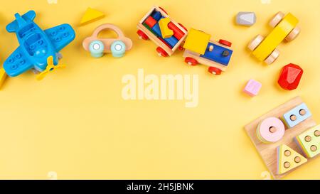 Baby Kinder Spielzeug für Kinder. Pädagogisches Spielzeug aus Holz und Kunststoff auf gelbem Hintergrund. Draufsicht, flach liegend Stockfoto