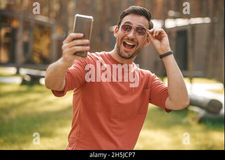 Fröhlicher Mann, der Selfie auf dem Smartphone gemacht hat Stockfoto