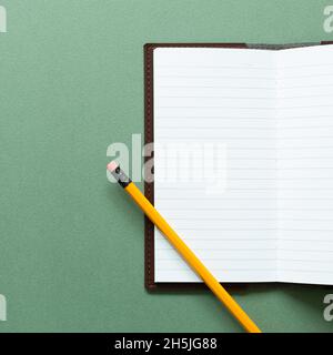 Öffnen Sie Notizbuch und Bleistift auf grünem Hintergrund. Draufsicht, Kopierbereich Stockfoto