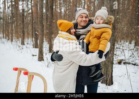 Familie am Heiligabend-Wochenende zu Fuß durch den Winterwald. Stockfoto