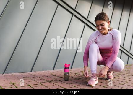 Fitness-Mädchen in rosa Sportswear binden Schnürsenkel auf Turnschuhe Stockfoto